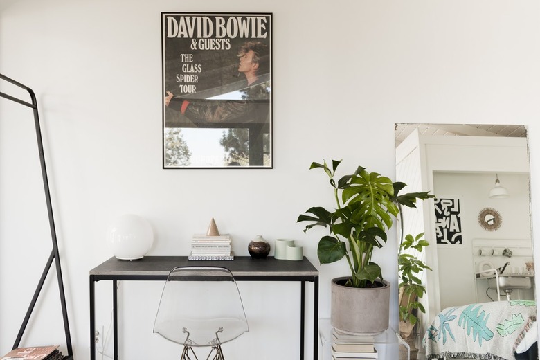 a vintage david bowie poster above a small, simple black metal desk
